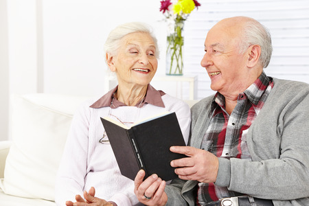 senior citizen couple reading a book in a retirement home