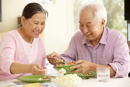 senior Asian couple sharing meal at home