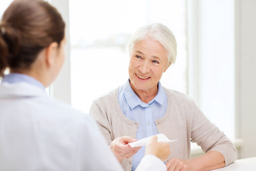 doctor giving prescription to happy senior woman at hospital