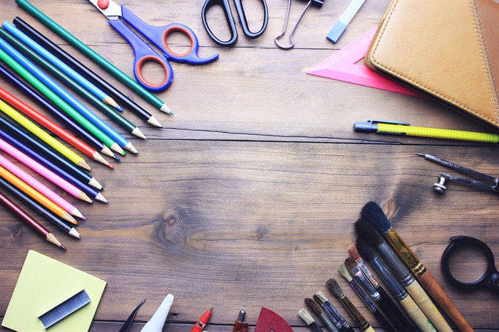 Paint brushes, colored pencils, and other art supplies are laid out in a circular pattern