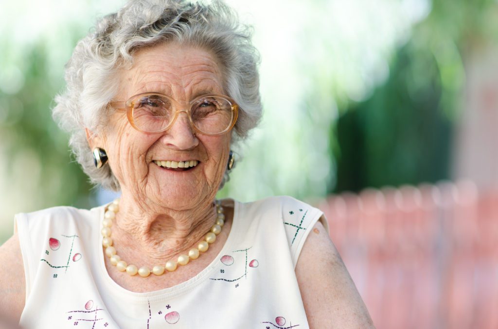 An elderly woman in round glasses laughing