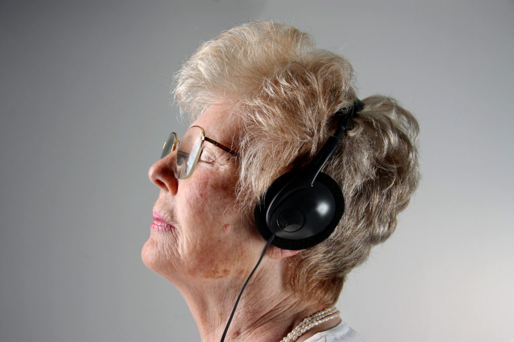 A senior woman listens to music on a set of headphones