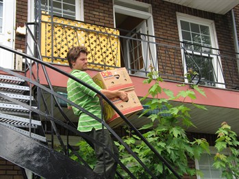 a man carries boxes down a flight of exterior apartment stairs