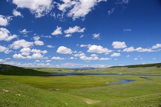 a blue sky looms over a serene green valley