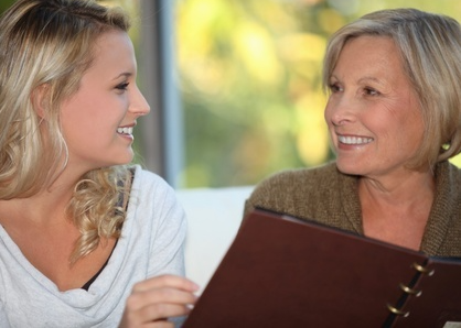 a mother and daughter looking through a scrapbook