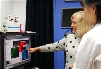 a woman points toward to a scan on a computer while standing next to her doctor