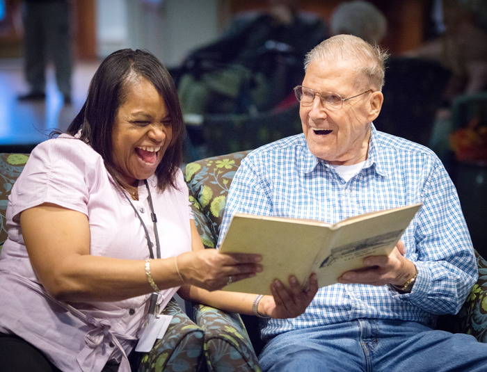 cmss staff member and older man read a book about when memory care is needed