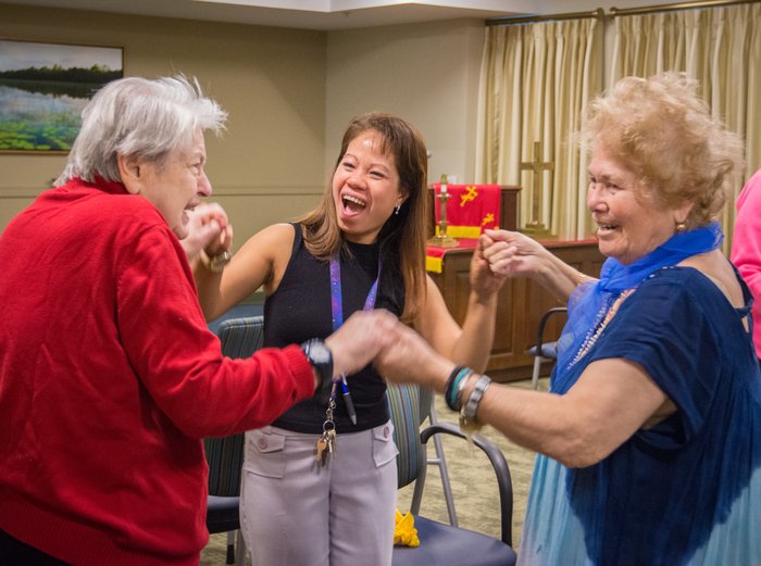 A group of three woman smile while holding each others' hands