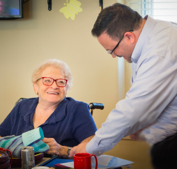 A woman in a wheelchair smiles up at the gentleman next to her