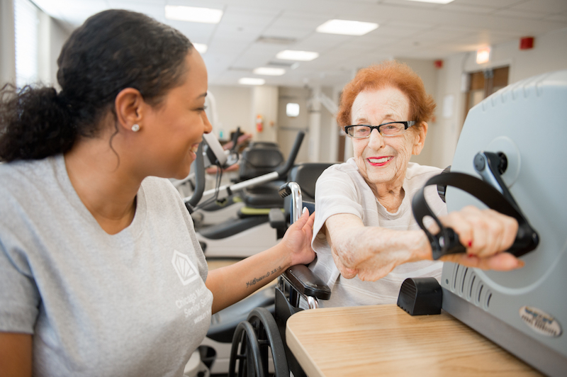 Woman assisting older woman with cardiac therapy machinery