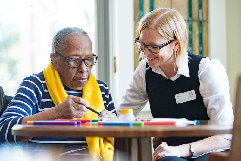 Older woman and CMSS staff member complete an art project as part of CMSS's memory care services