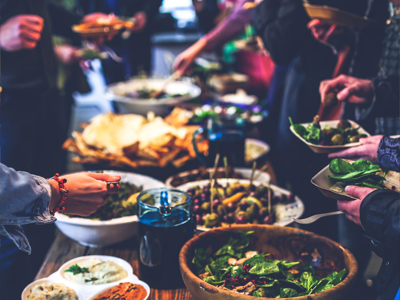 People fill up their plates along a stylish potluck table