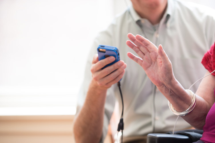 A hand hold a small blue portable music player and another hand stands raised