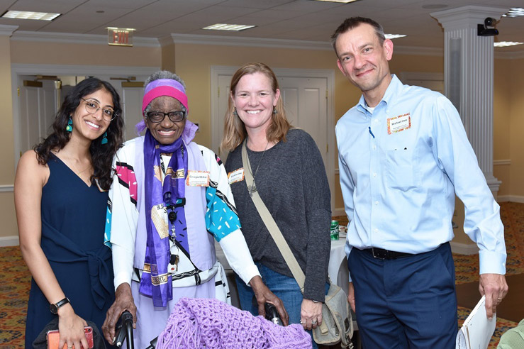 Four people of varying ages stands together smiling for a photo op