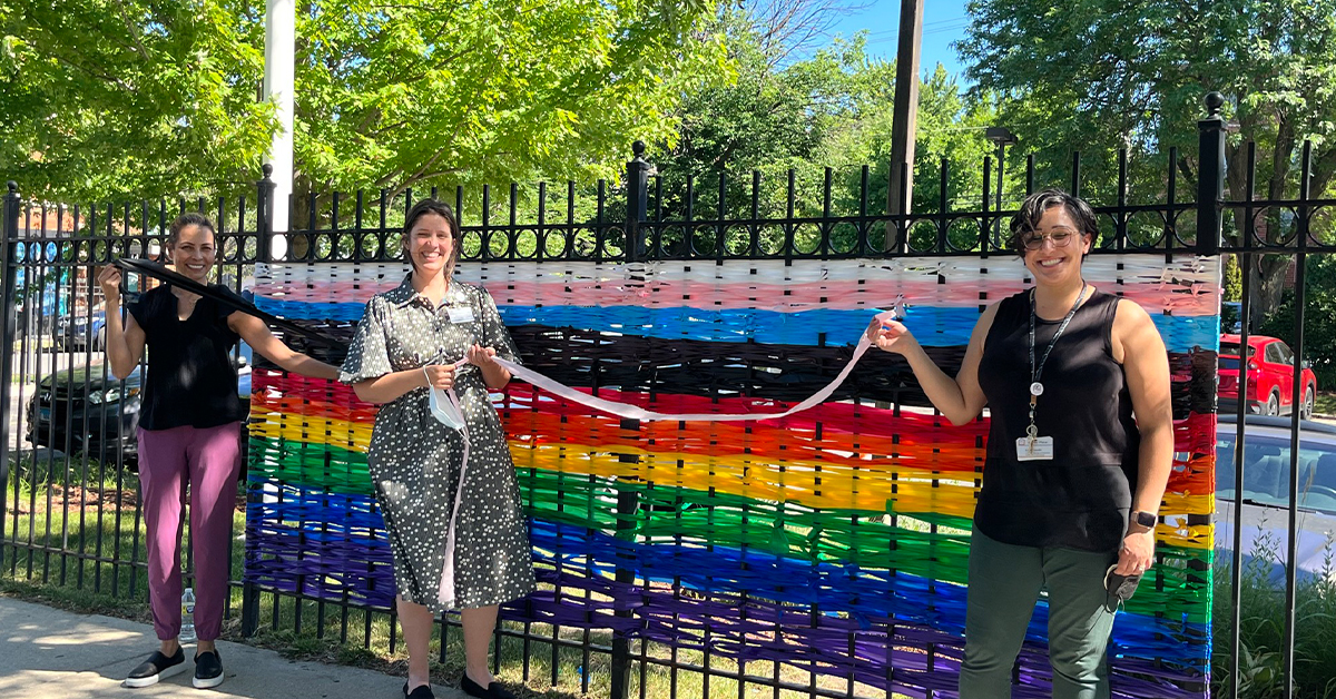 Image of CMSS staff putting up rainbow ribbon for a Pride event.