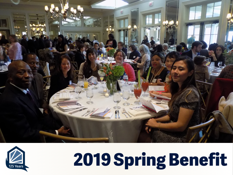 A table of people in a beautiful ballroom smile for the camera.