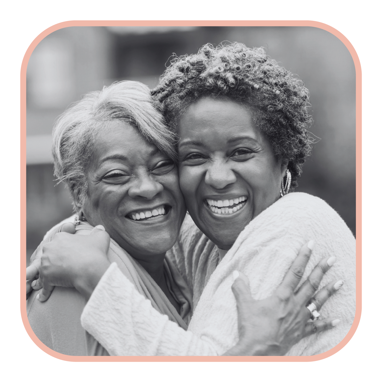 Black and white image of two senior women hugging and grinning.