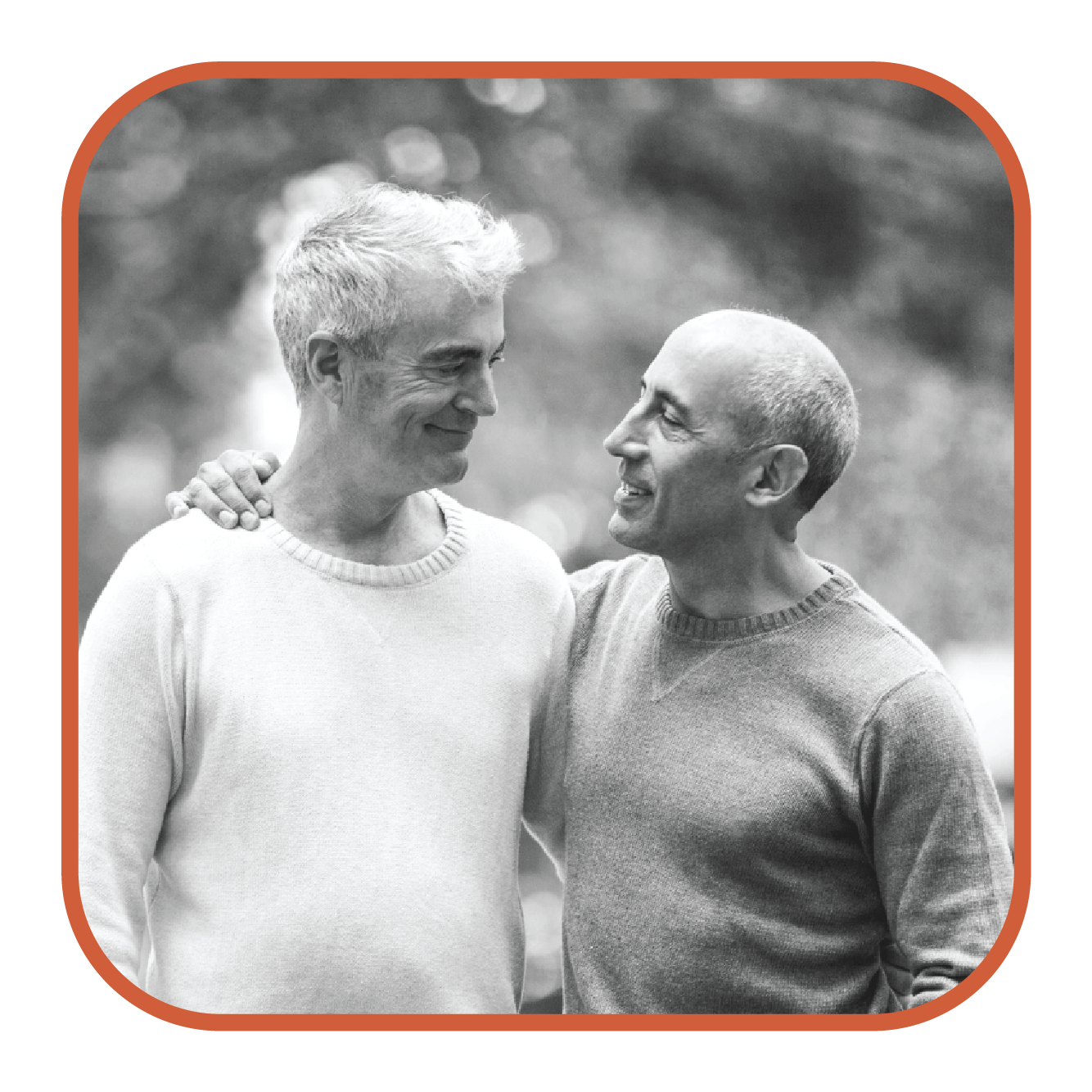 A gay senior couple pause and look at each other while walking with their arms around each other.