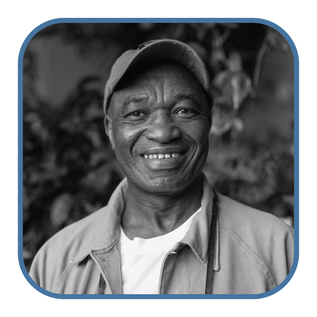An older African American man in a baseball cap smiles at the camera.