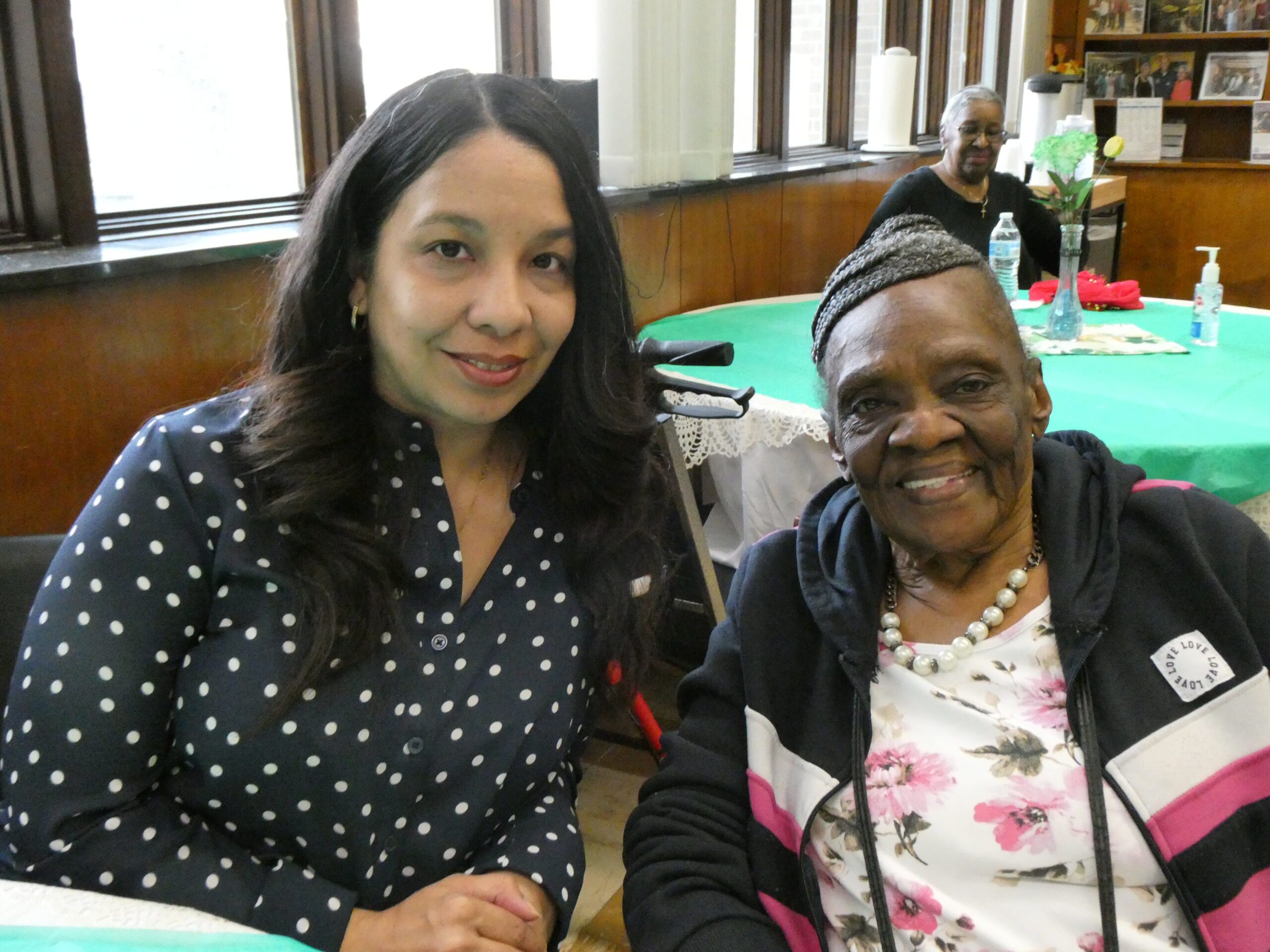 A woman sits next to an older woman and smiles for the camera.