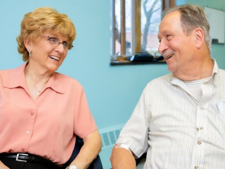 Two LGBT+ older adults smiling at each other at West Suburban Senior Center.